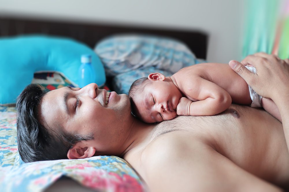 a baby in bare body peacefully sleeping on the body on his father with skin to skin touch. paternity concept parenting photo.