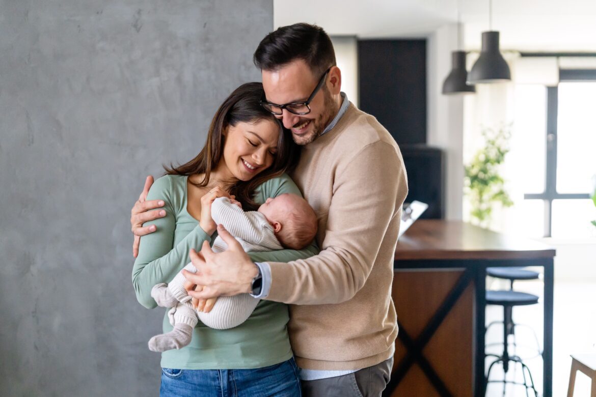 Peaceful young married couple enjoying being family, parents, holding new born baby in arms