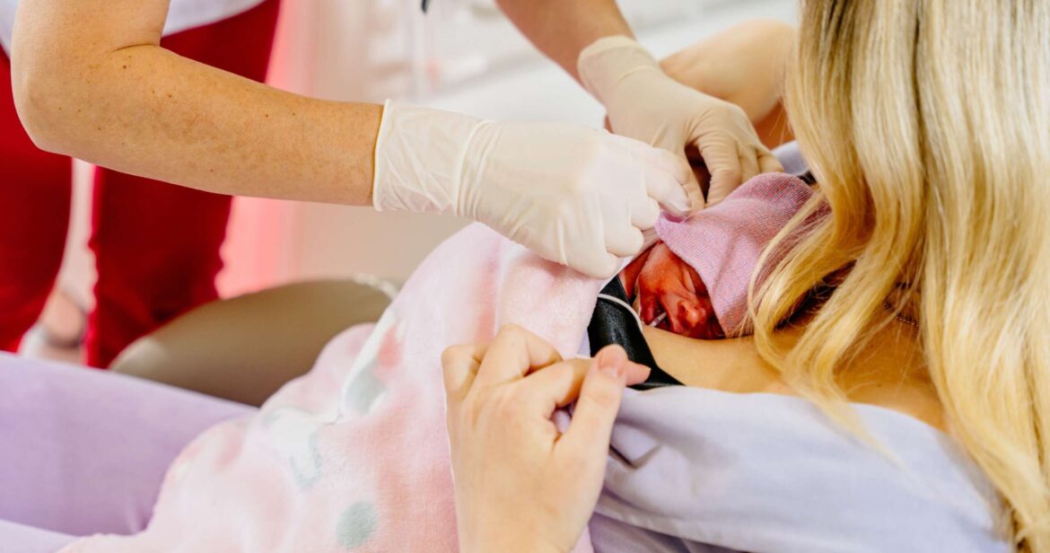 Mom hugs and holds in her arms a premature prematurely born girl in intensive care for a newborn. Skin to skin contact. Medical worker help. Kangaroo care concept.